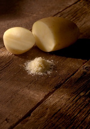 A potato cut in half with potato flakes on the table surface.