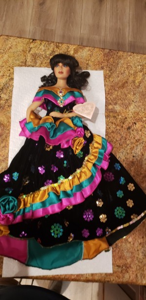 Value of a Franklin Heirloom Doll - dark haired doll wearing a long black dress with pink, teal, and gold ruffles and sequins