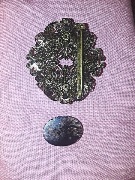 A metal brooch with the stone removed.