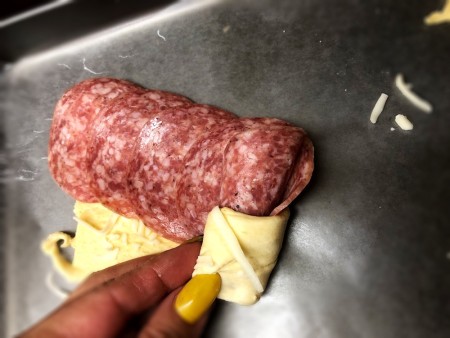 rolling dough around salami