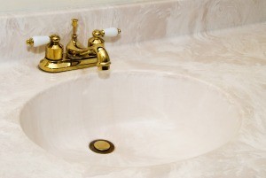 A cultured marble sink with gold fixtures.