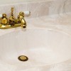A cultured marble sink with gold fixtures.