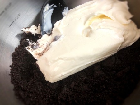 adding cream cheese to ground cookies