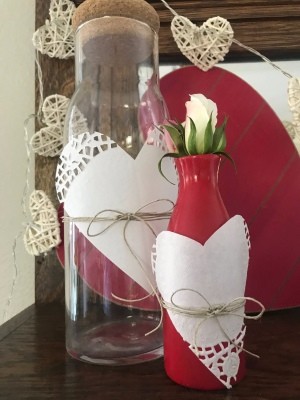 Transform any Vase into a One with a Valentine's Theme - clear bottle and red vase decorated with paper doily hearts