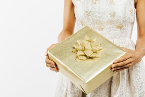 Golden wedding gift in the hands of a woman wearing a white dress.