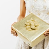 Golden wedding gift in the hands of a woman wearing a white dress.