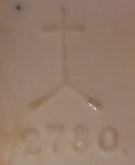 The makers mark and identification number on a ceramic figurine.