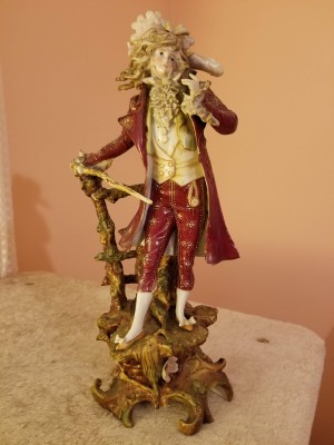 A ceramic figurine of a man in a fancy hat.