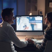 A couple looking at a computer screen, showing a healthcare website.