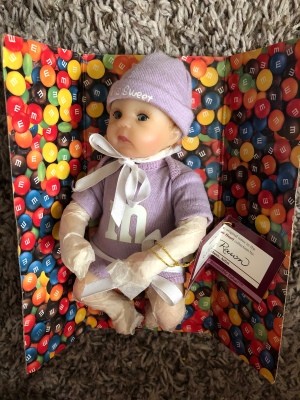 A purple M&M baby doll from Ashton Drake.