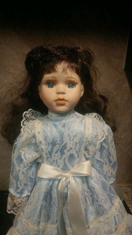 A porcelain doll in blue with dark hair.