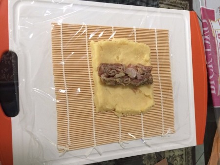 dough laid with meat filling on sushi mat
