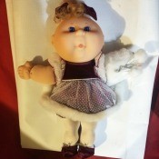 Identifying a Cabbage Patch Kid Doll - girl doll wearing a dark purple dress with fur trimmed lace overskirt, and a fur muff