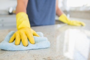 A person in gloves cleaning a kitchen counter.