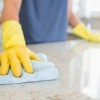 A person in gloves cleaning a kitchen counter.
