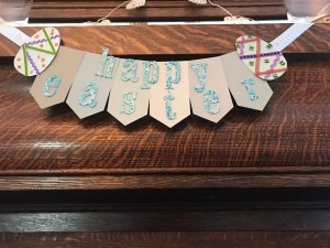 Happy Easter Banner - glue the eggs in place at the ends and add lengths of ribbon for hanging, front view of banner hanging on a wood mantle