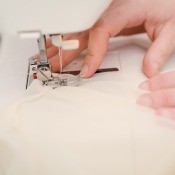 A wedding dress being sewn on a sewing machine.