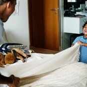 A father and son making a bed together.