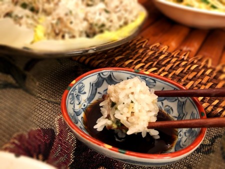 Sticky Rice Shumai dipped in bowl of sauce