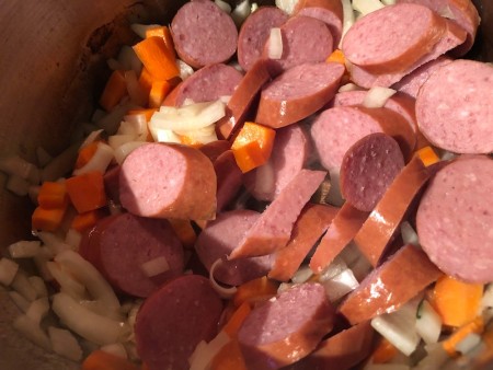 adding sausage to carrots & onions