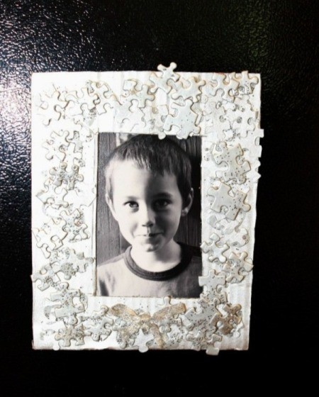 painted puzzle piece photo frame with a young boy's photo inside
