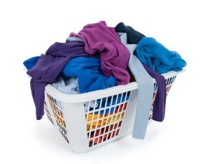 A white laundry basket full of clothing.