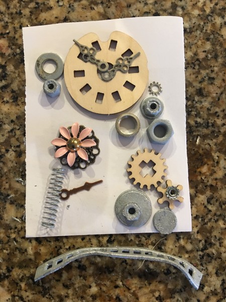 Steampunk Bottle - lay out supplies and embellishments on pieces of paper to design the back and the front, take photos