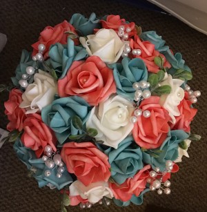 A wedding bouquet with teal and pink roses.