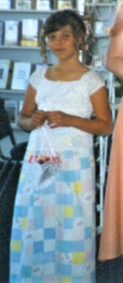 A flower girl in a white top and a handmade skirt.