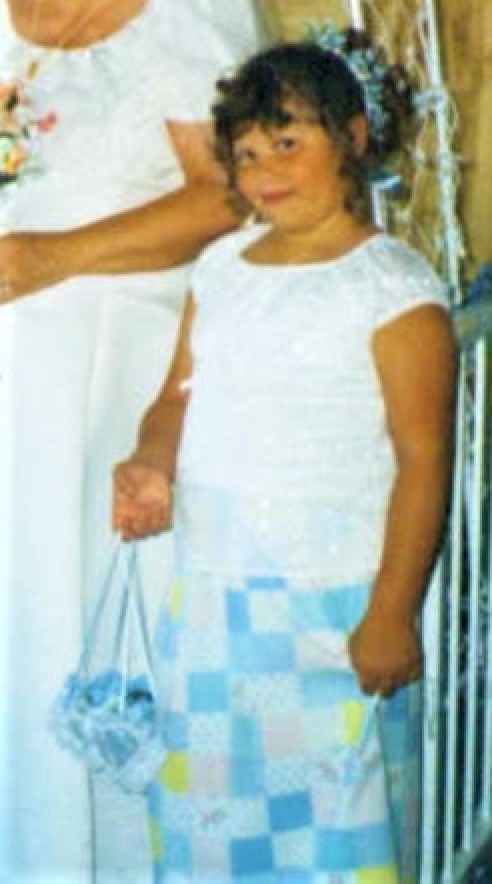 A flower girl in a white top and a handmade skirt.