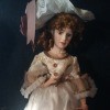 Value of an Ashley Belle Doll - doll wearing a large lace trimmed hat and a dress with lace bodice and white skirt with bows