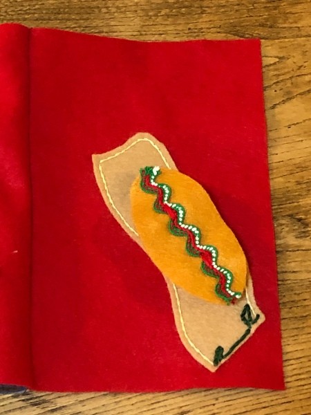 Child's Felt Book - sidewalk sewn in place, a bit of green grass stitched at one end, decorated skateboard sitting in place