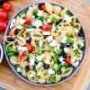 A bowl of Greek pasta salad with tomatoes, olives and feta cheese.
