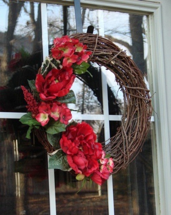 A grapevine wreath decorated with red flowers