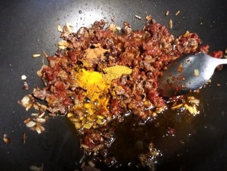 spices added to meat in pan