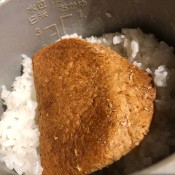 A piece of bread in a pot of mushy rice.
