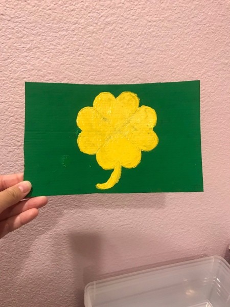 St. Patrick's Day Theme Hanging Wall Sign - hand holding the wall hanging against a pink background