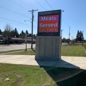 Picking Up Free School Lunch During COVID-19 Closures - school sign with times for meals