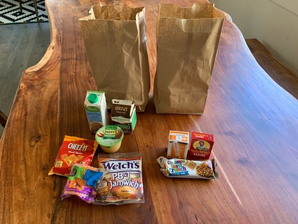 A school lunch with a sandwich, drink and snacks.