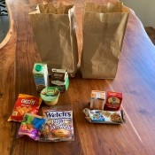 A school lunch with a sandwich, drink and snacks.