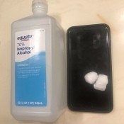 Wipe Down Electronics - bottle of alcohol and cotton balls on top of a cell phone