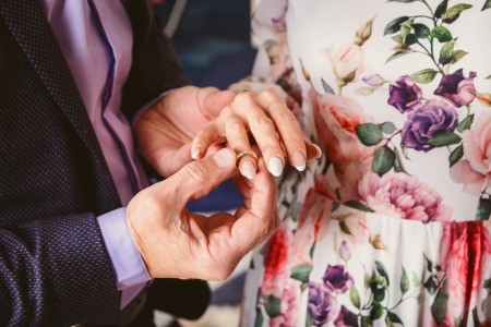 A man placing a ring on the hand of a woman.