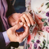 A man placing a ring on the hand of a woman.