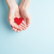 Two hands offering a red paper heart