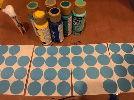 Splatter Paint Sticker Circle Garland - blue circular stickers, craft paint bottles, and a clothespin brush