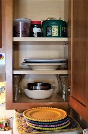 A cupboard with the lower shelf supported by glass vases.