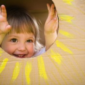 A child looking through a sun in a cardboard box.