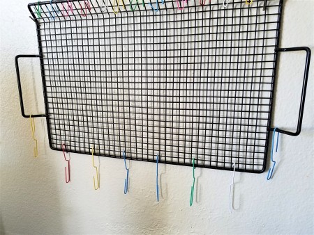 Hanging Necklaces Using Re-purposed Items - black wire tray on wall with nail in upper corners and opened paperclips in place
