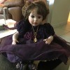 Identifying a Porcelain Doll - sitting doll wearing a dark purple dress and gold chain with a heart shaped pendant