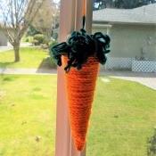 Crocheted Carrot - carrot hanging below a seed packet garland in the window